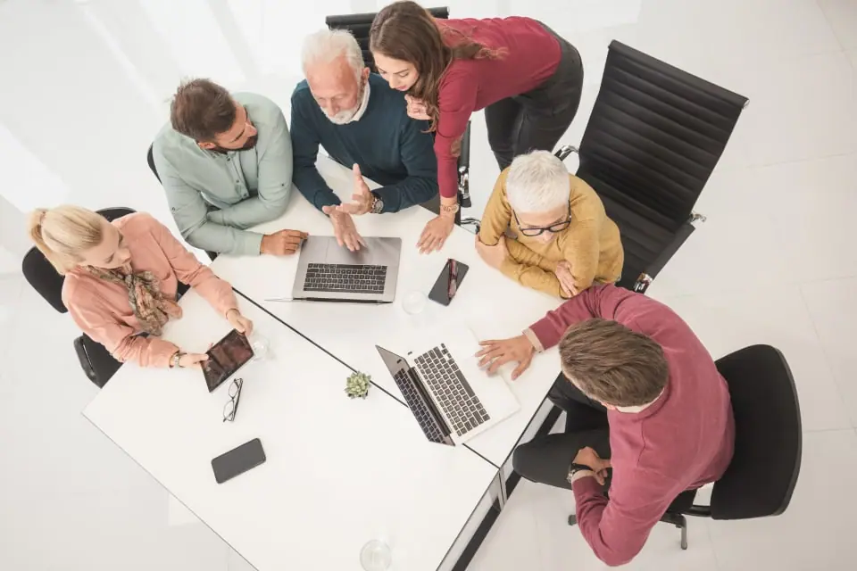 Specialists gathered around a table reviewing plan options on laptops and tablets